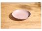 Lege roze kom op een lichte houten tafel met schaduwen.