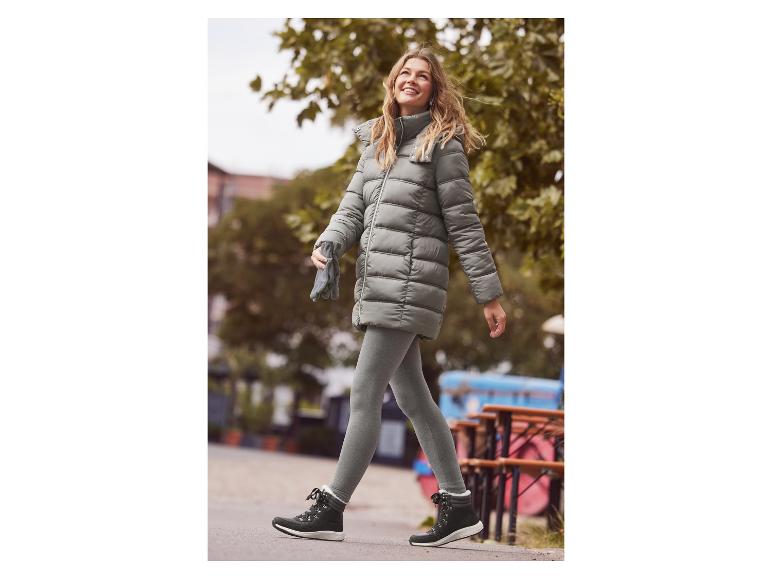 Een vrouw loopt op straat met een warme pufferjas en grijze leggings.