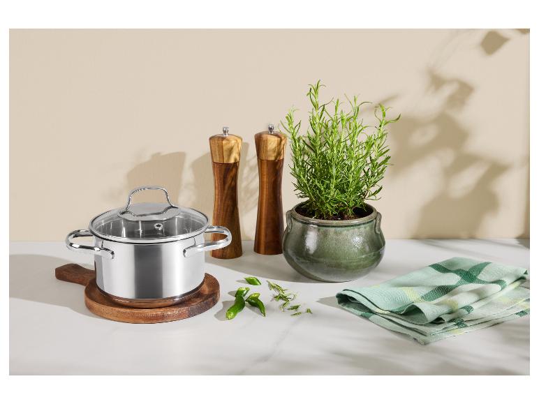 Roestvrijstalen pan met glazen deksel, houten zout- en pepermolens en een rozemarijnplant.