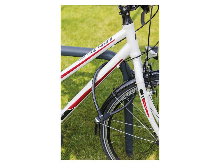 Witte fiets met rode accenten, vastgezet aan een fietsenrek met een zwart kabelslot.
