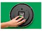 Een hand plaatst een batterij in het mechanisme van een roze wandklok.