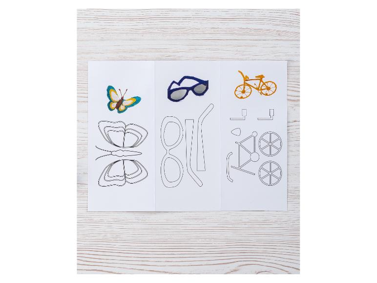 Een vlinder, zonnebril en een fiets, met hun sjablonen, op een houten tafel.