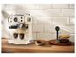 Crèmekleurig espressomachine zet koffie in twee kopjes, met koekjes en koffiebonen ernaast.