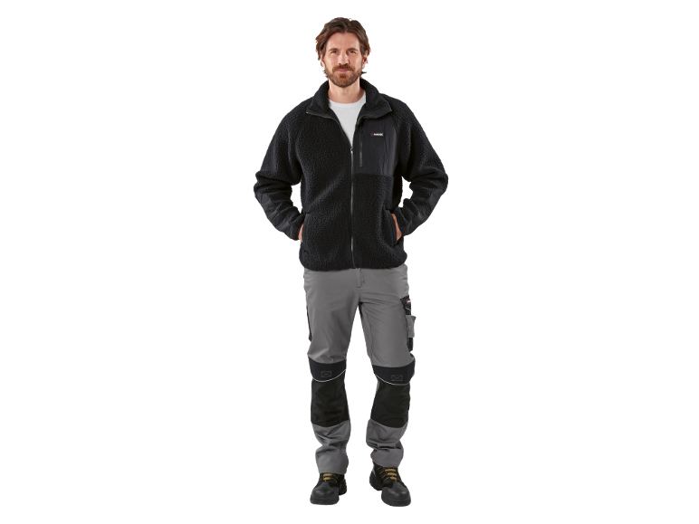 Man in een zwart fleecejack en een grijze werkbroek.