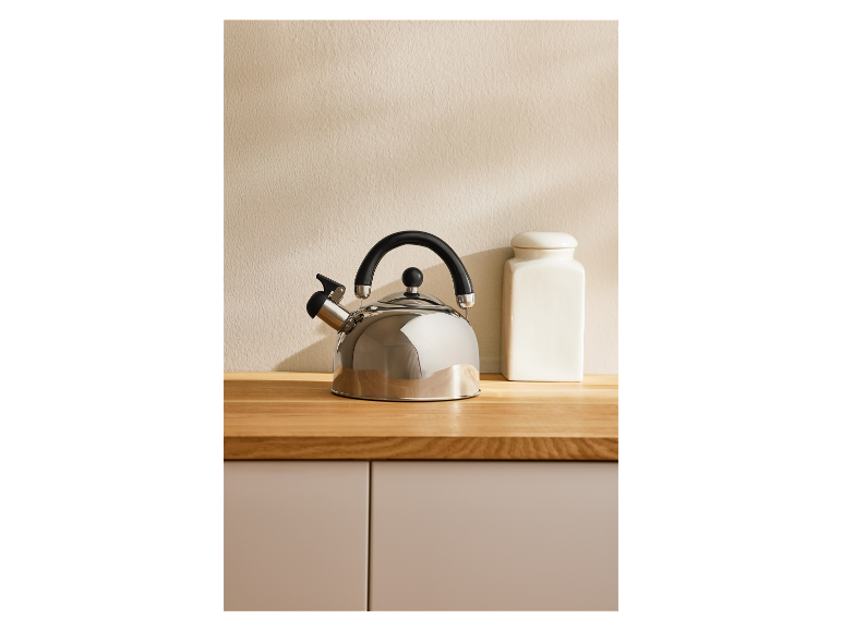 Een RVS waterkoker en een witte container op een houten aanrecht.