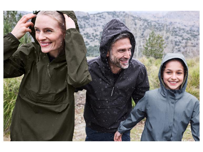 Een gelukkig gezin draagt regenjassen tijdens een wandeling in de regen.