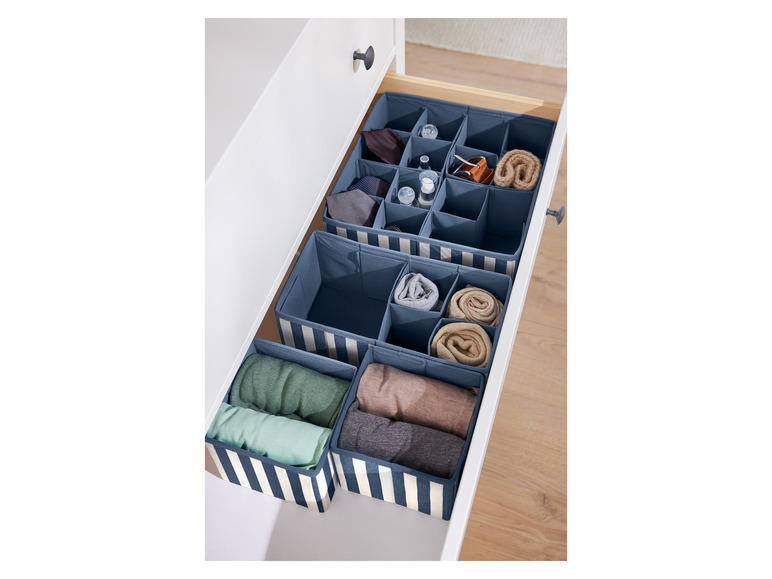 Opbergbakken in een lade met kleding en accessoires.