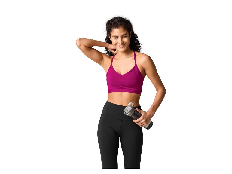Vrouw in fuchsia sportbeha en zwarte legging, met een waterfles.