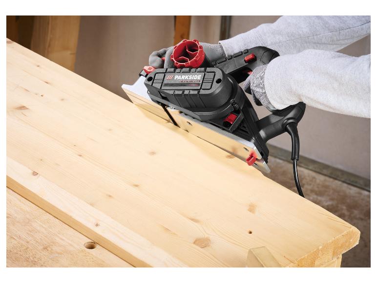 Persoon gebruikt een invalzaag om een houten plank op een werkbank te zagen.