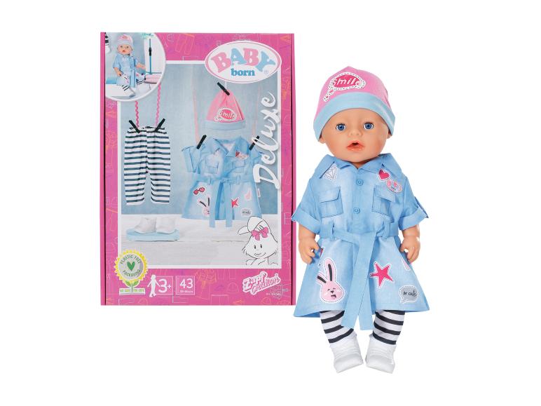 BABY born Deluxe pop in blauwe jurk met konijntjes en roze muts, naast de verpakking.