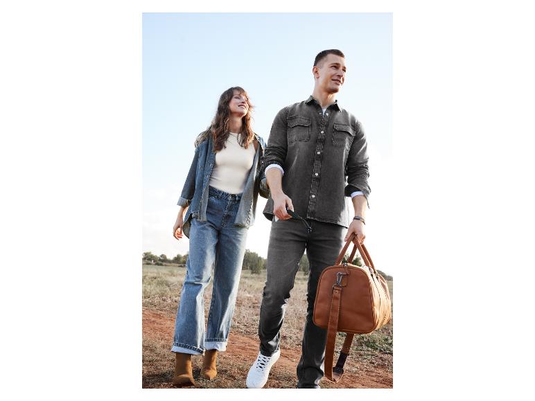 Een stel loopt met een lederen weekendtas over een onverharde weg.