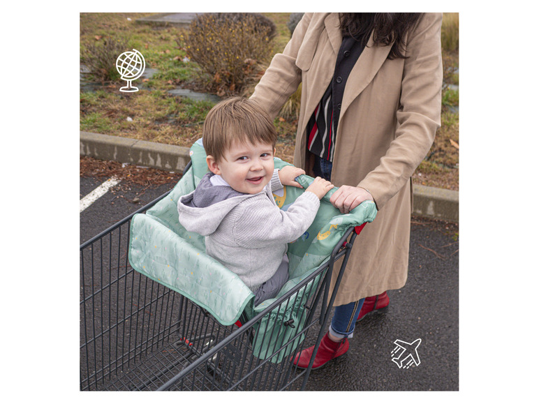 Een kind zit in een winkelwagen met een groene beschermhoes.