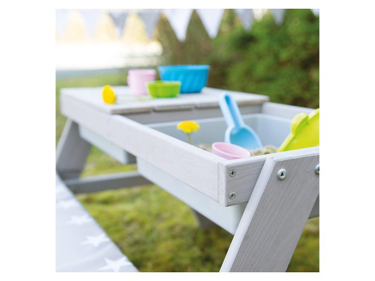 Zandtafel met kleurrijk speelgoed en zand in een tuin.