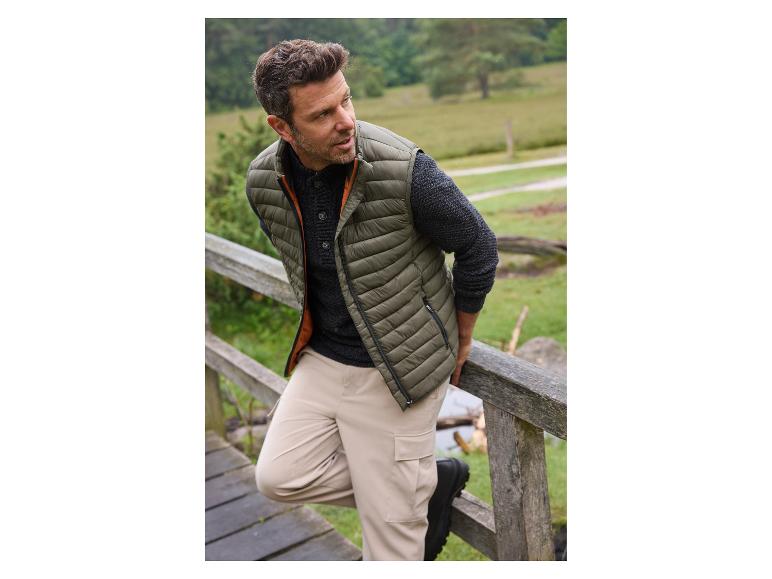 Man in een groene donsjas en beige broek.