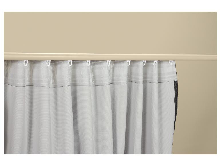 Wit gordijn met haken, hangend aan een beige gordijnroede.