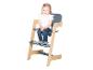 Peutermeisje zit lachend in een houten en grijze kinderstoel.