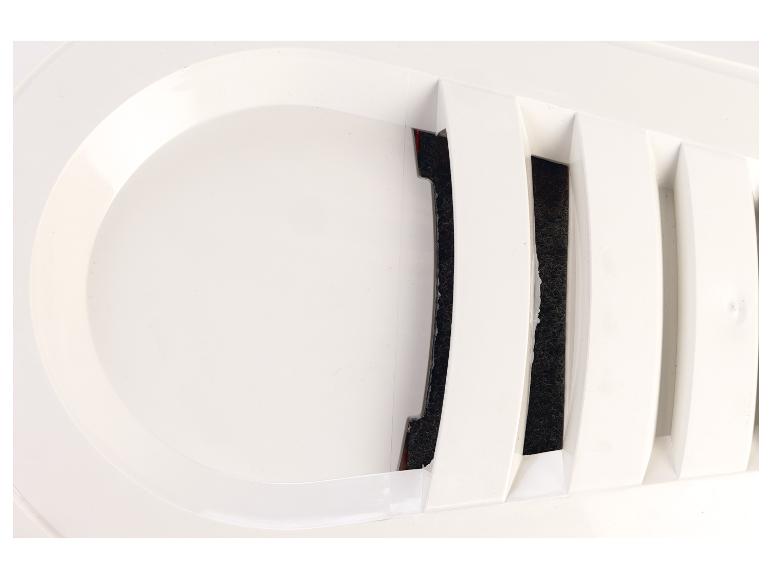 Close-up van een wit ventilatierooster met donker filtermateriaal zichtbaar achter de lamellen.