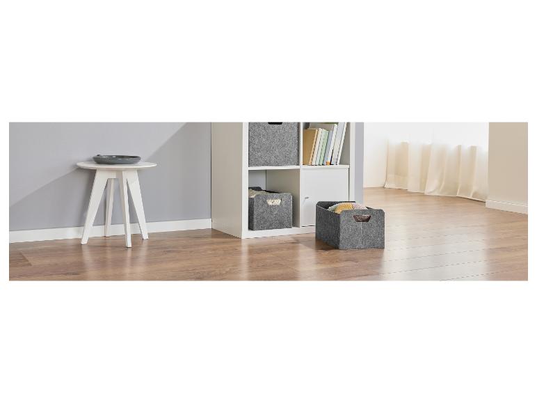 Lichte kamer met houten vloer, witte bijzettafel en grijze vilten manden.