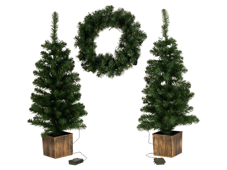 Twee kunstkerstbomen in potten en een kerstkrans, allemaal verlicht.