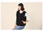 Vrouw met zwarte muts, wit shirt en zwart fleecevest.