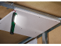 Een heldere werklamp hangt aan een metalen plafondframe en verlicht een gipsplaat.