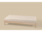 Lichtbeige matras op een houten bedframe tegen een beige achtergrond.