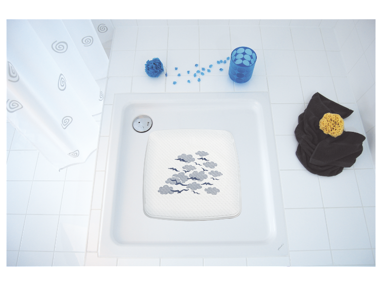 Badmat met wolken- en vogeldruk in een witte douchecabine.