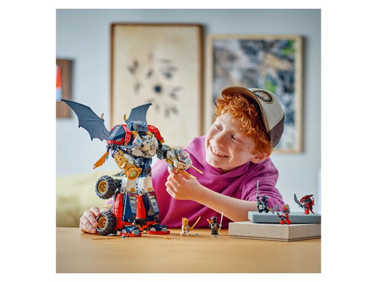 Blije jongen speelt met een grote LEGO Ninjago mech en minifiguren op een tafel.
