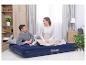 Lachend stel ontspant op een blauw Bestway luchtbed op de woonkamervloer.