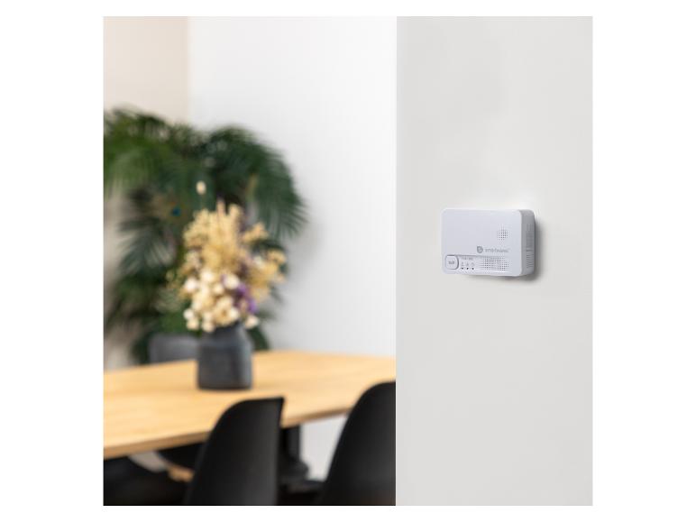 Een wit smart home-apparaat gemonteerd aan een muur in een modern interieur.