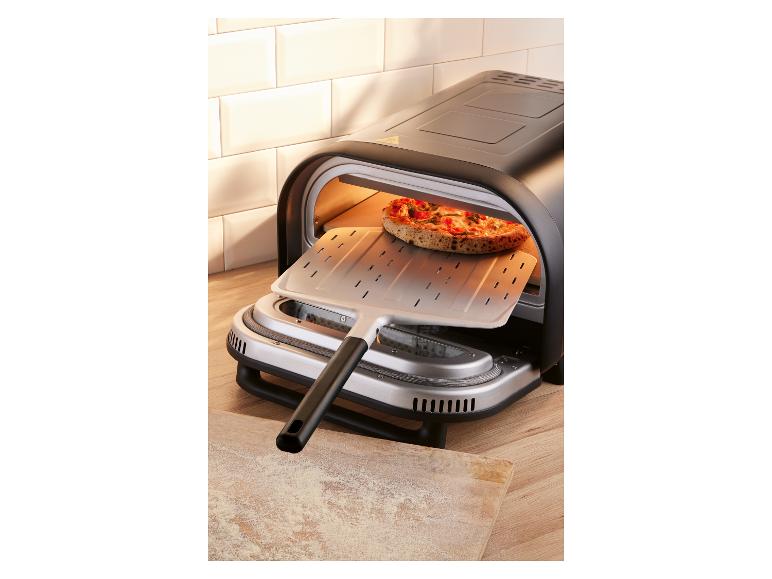 Elektrische pizzaoven met een pizza die met een pizzaschep wordt ingeschoven.