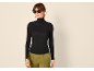 Vrouw in zwarte coltrui, groene broek en zonnebril.