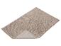 Beige badmat met een pluizige textuur en een opstaande rand.