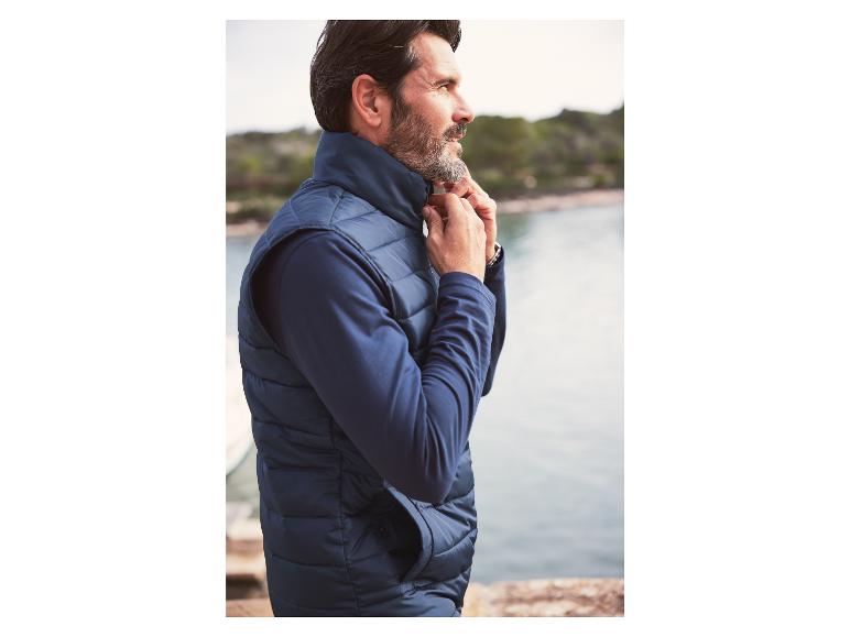 Een man draagt ​​een blauwe puffer-vest en een lange mouw trui.