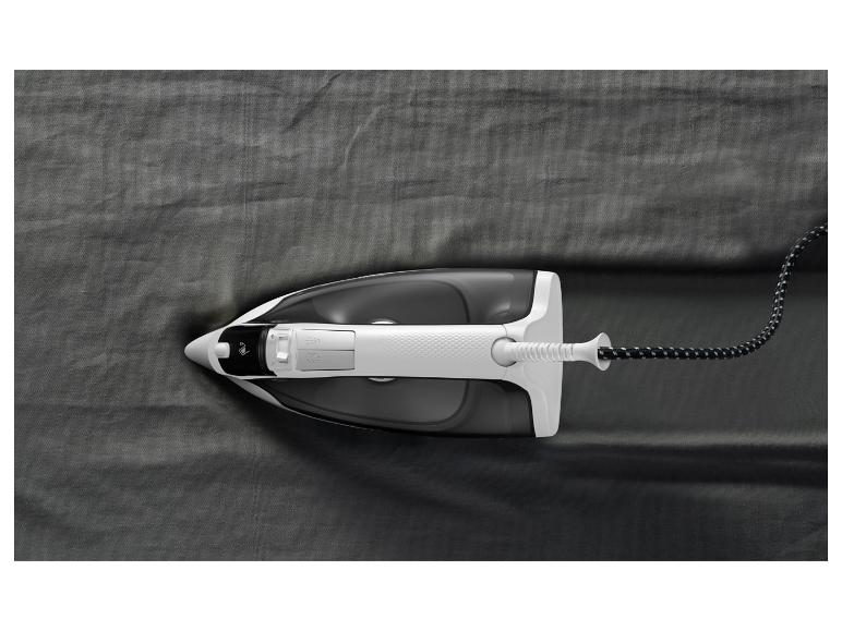 Een strijkijzer op een donkergrijze stof, dat kreukels gladstrijkt.