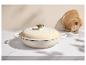 Crèmekleurige gietijzeren braadpan met gouden knop, op een marmeren aanrecht.