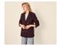 Lachende vrouw in getextureerde bordeauxrode blazer, wit T-shirt en lichte jeans.
