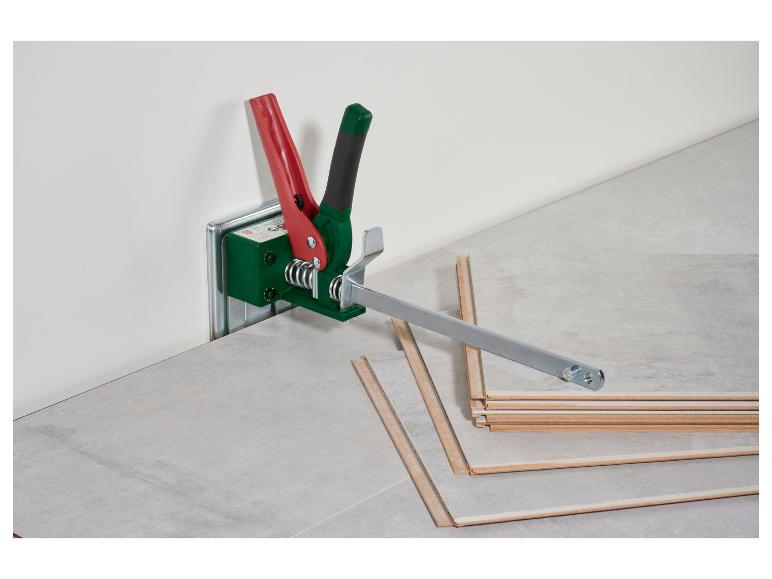 Laminaatlegger met rode en groene handgrepen, op een laminaatvloer.