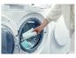 Vrouw laadt wasgoed, inclusief handdoeken, in een wasmachine.
