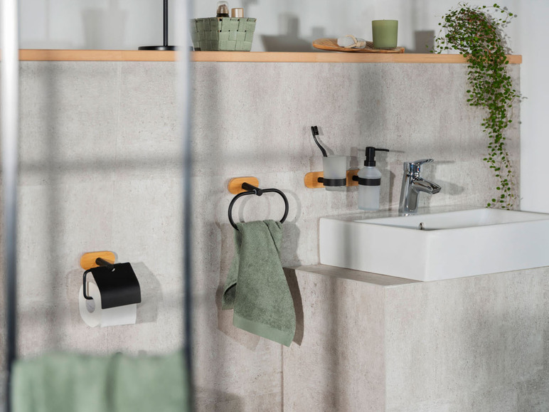 Een badkamer met een wastafel, een handdoekhouder, een toiletrolhouder en een plantenhanger.