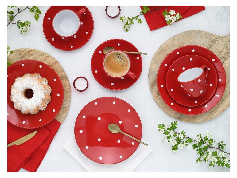 Rood servies met stippen, koffie, cake en bloemen op een tafel.