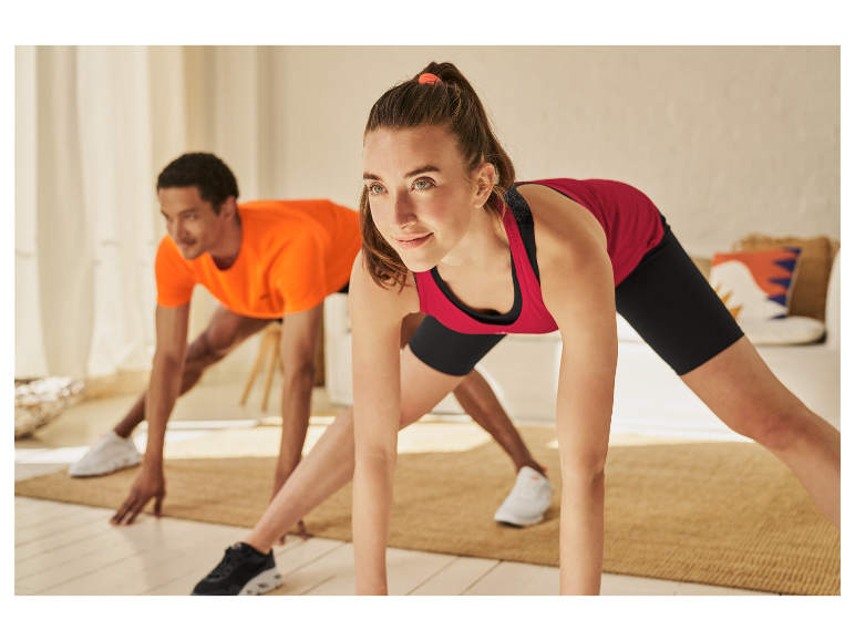Twee personen doen stretchoefeningen in hun sportkleding thuis.