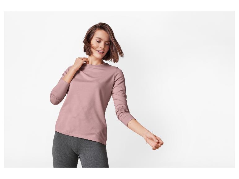 Vrouw in roze blouse met lange mouwen en grijze legging