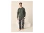 Lachende man in pyjama met lange mouwen en geruite broek, blootsvoets staand.