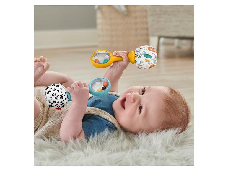 Blije baby speelt met twee Fisher-Price rammelaars op een pluizig kleed.