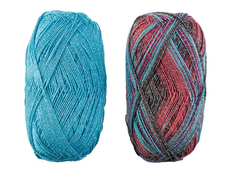 Twee bollen garen, één turquoise en één veelkleurig, beide met zilveren glitters.
