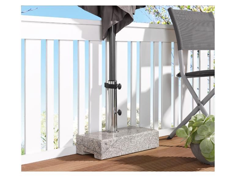 Granieten parasolvoet op een houten terras met een stoel en een plant.