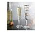 Twee versierde champagneglazen, één met gouden harten, de andere met muzieknoten, naast een champagnefles.