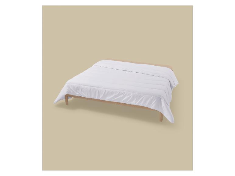 Wit dekbed op een houten bedframe.