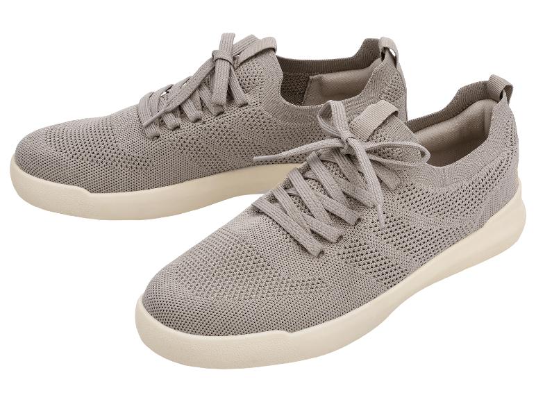 Een paar grijze gebreide sneakers met beige zolen.